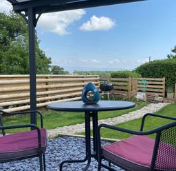 A garden with table and chairs, grill, and path at The Haven in Penrith