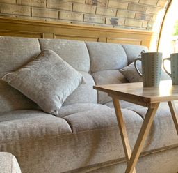 A sofa with a cushion and a table with mugs at Cosy Escape Sheerness