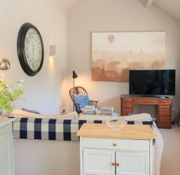 A living room with a television and a clock at Foxhill Farm Barn Cheltenham