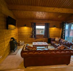 A living room with a sofa, coffee table, and a wood stove at Pineshadow Lodge in Louth