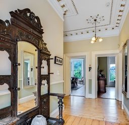 A hallway with an ornate cabinet and mirror at Fountain Hill House in Londonderry