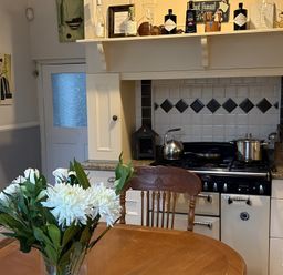 A kitchen with a stove and table with flowers at Fountain Hill House in Londonderry