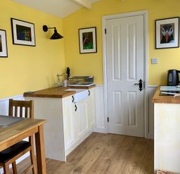 A kitchen with a table and chairs at Bluebell Shepherd’s Hut in Llanfairpwllgwyngyll