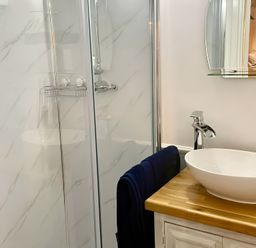 A bathroom with a shower and sink at Bluebell Shepherd’s Hut in Llanfairpwllgwyngyll
