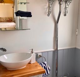 A bathroom with a sink and mirror at Bluebell Shepherd’s Hut in Llanfairpwllgwyngyll
