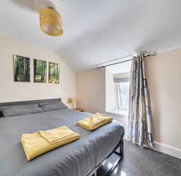 A bedroom with a bed and wall art at Sea view cottage in Penmaenmawr