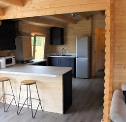 A kitchen with a sink, refrigerator, and stools at Cotswold Nights Away in Evesham