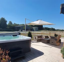 A patio area with a hot tub and outdoor furniture at Fox Lodge in York