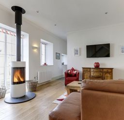 A living room with a wood stove and sofa at Poppyfields Stable in Redruth