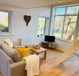 A living room with a sofa and a television at Honey Bee Cottage in Welshpool