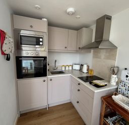 A kitchen with a microwave, oven, kettle, and sink at Honey Bee Cottage in Welshpool