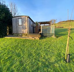 A wooden hut with a fenced area and pathway at Shepherds hut Dumfries