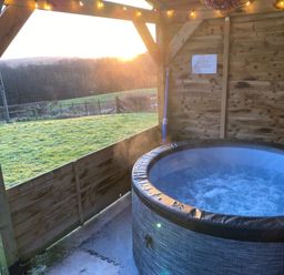A hot tub in a wooden structure with a sunset view at Shepherds hut Dumfries
