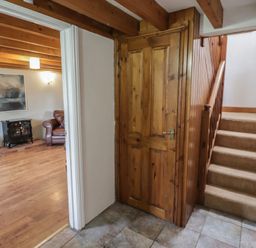 A hallway with a staircase and door at Rhosgranog Cottage, Llandeloy near Solva