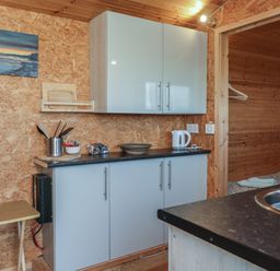 A kitchen area with cupboards and sink at Rhosgranog Shepherds Hut Llandeloy near Solva