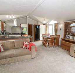 A living room with a sofa, dining table and kitchen at No 8 Hillcote Lodge in Cockermouth