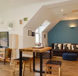 A living room with a sofa and television at Lowenna Watergate Bay near Newquay