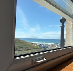 A view of the ocean and hills through a window at Lowenna Watergate Bay near Newquay