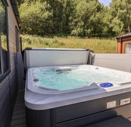 A hot tub on a deck at Cedar Lodge 2 Bedrooms with hot tub in Delamere