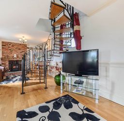 A living room with a staircase and television at Bank House Cottage in Glasson Dock