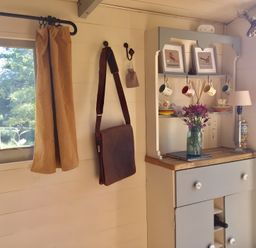 A kitchen with a cupboard and a vase of flowers at Cosy Shepherd’s Hut in Longhope