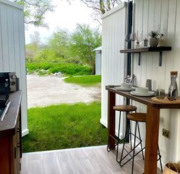 A kitchen with a wooden table and stools at Trethowels Hidden Huts in St. Austell