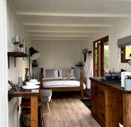 A bedroom with a bed and dining area at Trethowels Hidden Huts in St. Austell