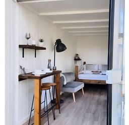 A interior view with a bed, sofa, and table at Trethowels Hidden Huts in St. Austell