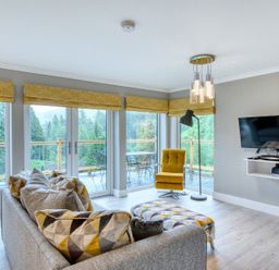 A living room with a sofa and television at Pinemarten Lodge Crianlarich