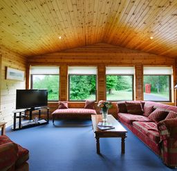 A living room with a television and sofa at Buzzard Lodge in Crianlarich