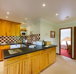 A kitchen with wooden cabinets and appliances at Buzzard Lodge in Crianlarich