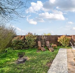 A garden with wooden chairs and a fire pit at Cosy Escape in Minster On Sea
