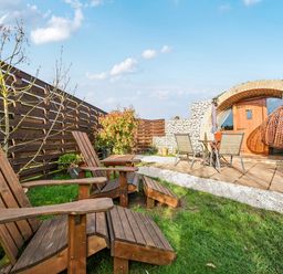 A garden with wooden chairs and a dining table at Cosy Escape in Minster On Sea