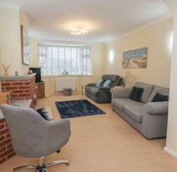 A living room with an armchair and sofa at Tudor Rose in Weymouth
