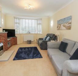 A living room with a sofa, armchair, and television at Tudor Rose in Weymouth