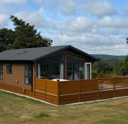 A lodge with a deck situated in a garden at Moorland View in Dobwalls