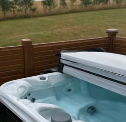 A hot tub with a cover and surrounding fence at Moorland View in Dobwalls