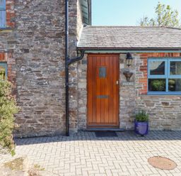 An entrance with a wooden door and stone wall at Pillars in Barnstaple