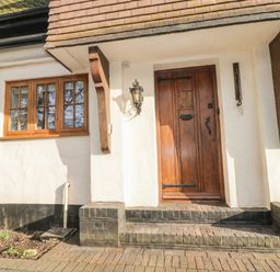 An entrance with a wooden door and window at Woodlands house in Ringwood