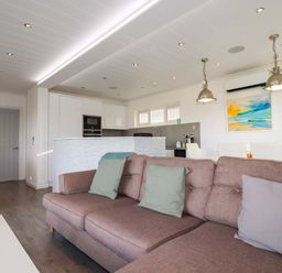 A living room with a sofa and kitchen area at 114 - The Residance in Redruth