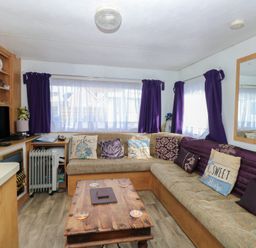 A living room with a sofa and coffee table at Whispering Meadows - 104 in Hemsby