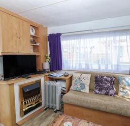A living room with a television and a sofa at Whispering Meadows - 104 Hemsby