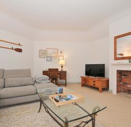 A living room with a sofa, table, and television at Cribba in Port Isaac