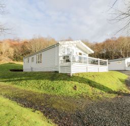 A house with a deck and driveway at Serenity Lodge in Wemyss Bay