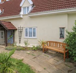 A garden with a wooden bench and lattice structure at Driftway Stables Retreat in Diss