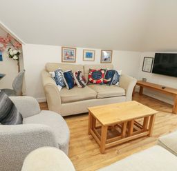 A living room with a sofa, coffee table, television and wall art at Flat 7 Weymouth