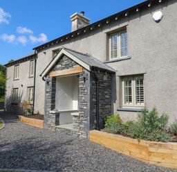 An exterior view of a house with a stone feature at Low House Cottage Ayside near Newby Bridge