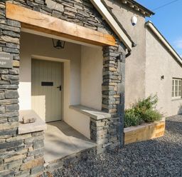 The entrance with a stone wall and front door at Low House Cottage Ayside near Newby Bridge