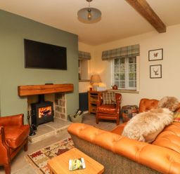 A living room with a sofa and television at Bridge House Cottage in Burn Bridge near Harrogate