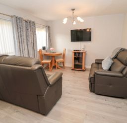 A living room with a sofa and a dining table at Primrose Cottage in Chathill